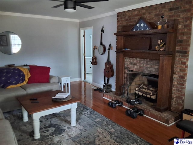 living room featuring hardwood / wood-style flooring, ceiling fan, ornamental molding, and a brick fireplace