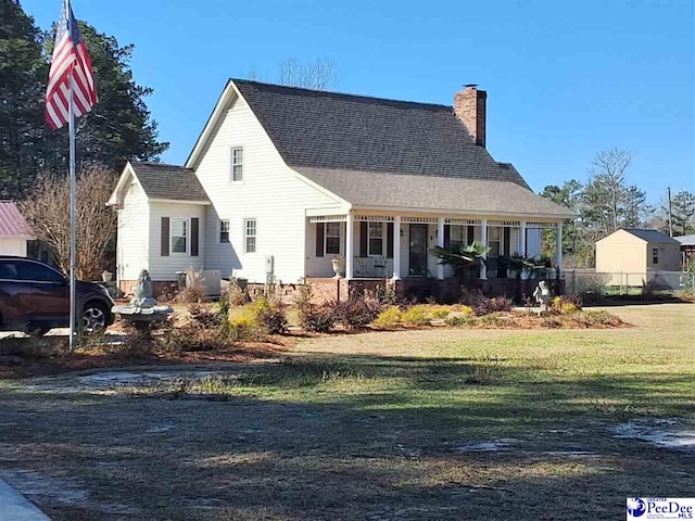 view of front of home with a chimney, a front lawn, a shingled roof, fence, and a porch