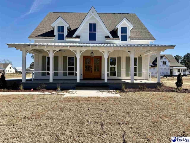 view of front of property featuring a shingled roof, a front yard, covered porch, and french doors