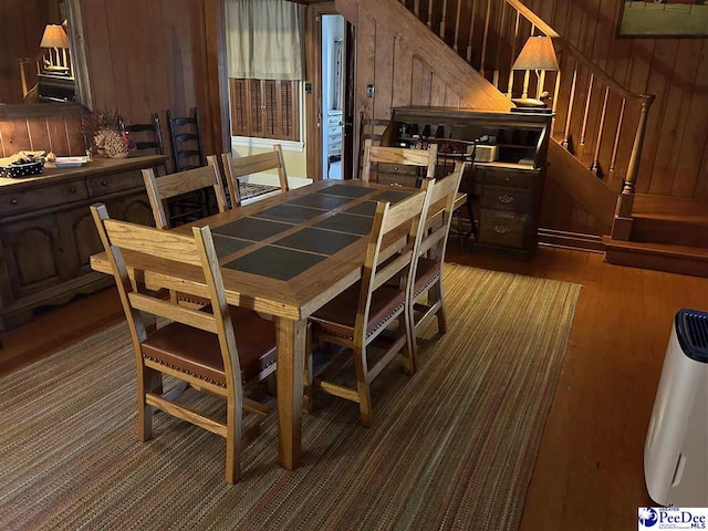 dining area featuring wooden walls and dark hardwood / wood-style flooring