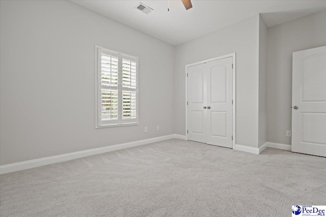 unfurnished bedroom with ceiling fan, a closet, visible vents, light carpet, and baseboards