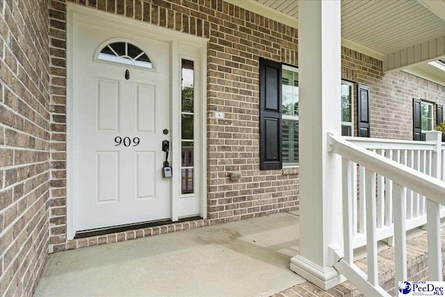 property entrance with covered porch and brick siding