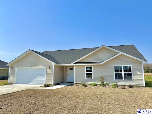 ranch-style house featuring an attached garage, concrete driveway, a front yard, and a shingled roof