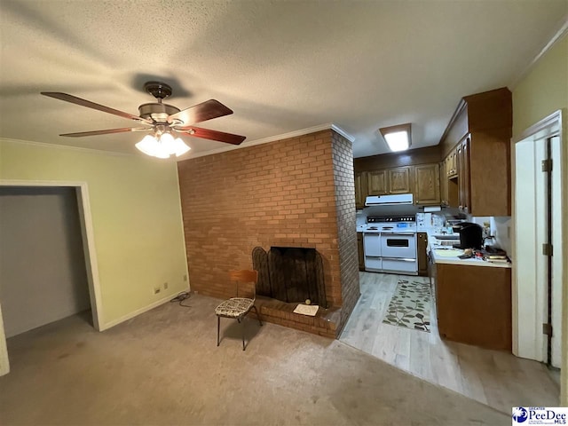 kitchen with a brick fireplace, a textured ceiling, ornamental molding, ceiling fan, and range with two ovens