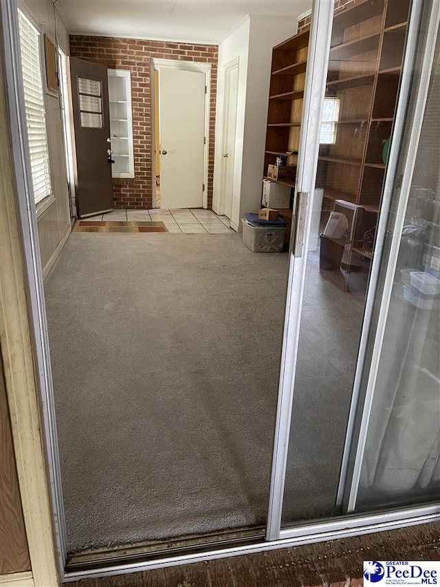 interior space featuring brick wall and light carpet