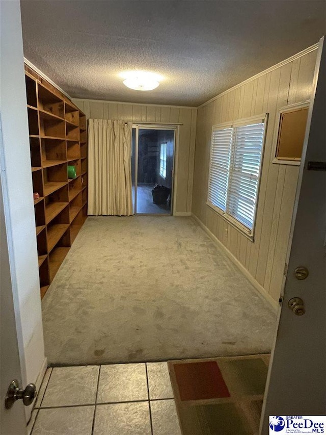 corridor featuring wood walls, a textured ceiling, and carpet