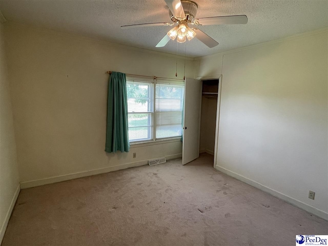 unfurnished bedroom with light carpet, ceiling fan, ornamental molding, and a textured ceiling