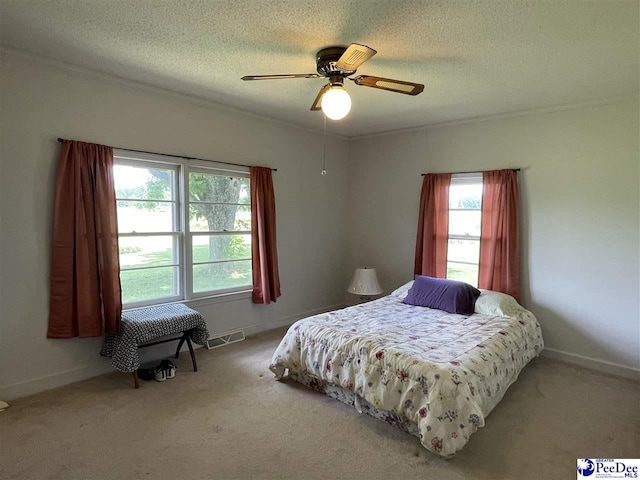 bedroom featuring ceiling fan, crown molding, carpet floors, and a textured ceiling