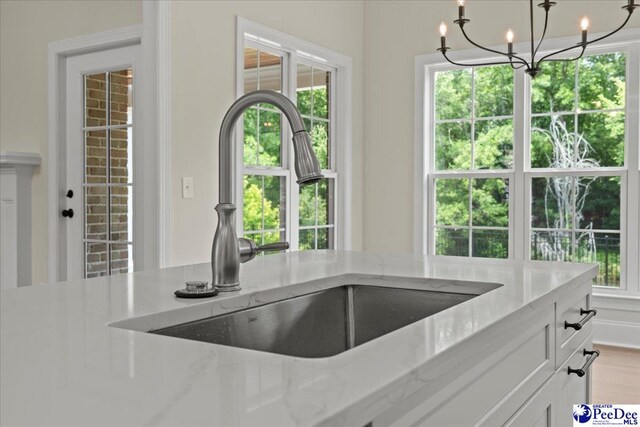 2528 Edinberg Way, Florence, SC 29501 - kitchen featuring a sink, a chandelier, white cabinets, light stone countertops, and decorative light fixtures