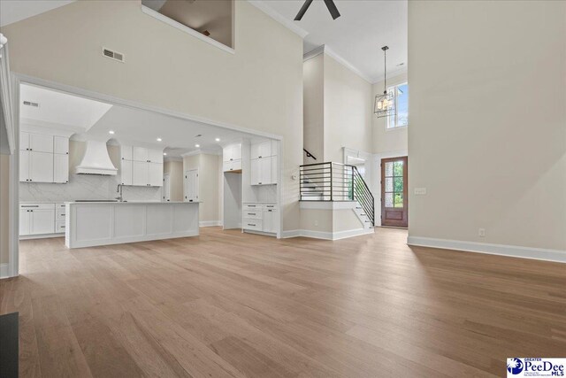 2528 Edinberg Way, Florence, SC 29501 - unfurnished living room with a towering ceiling, stairs, light wood-type flooring, ornamental molding, and baseboards