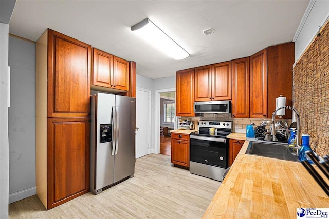 600 Greenway Dr, Florence, SC 29501 - kitchen featuring butcher block counters, light wood-type flooring, decorative backsplash, appliances with stainless steel finishes, and a sink