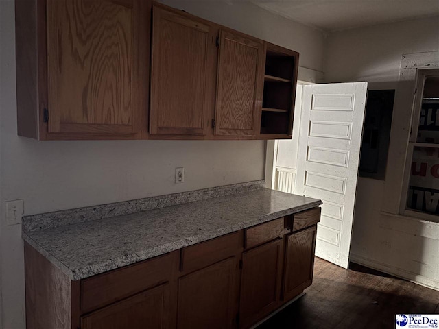 kitchen featuring dark wood-style floors, light stone counters, and open shelves