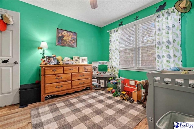 bedroom featuring ceiling fan, a textured ceiling, and light hardwood / wood-style flooring