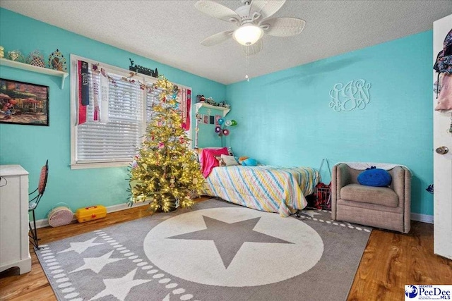 bedroom featuring hardwood / wood-style flooring, ceiling fan, and a textured ceiling