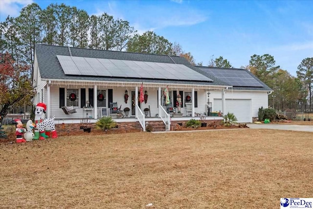 view of front of house with a garage, a front yard, solar panels, and covered porch