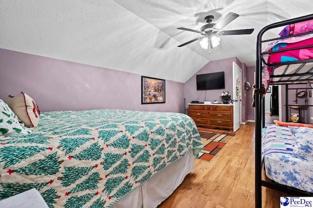 bedroom with lofted ceiling, ceiling fan, light hardwood / wood-style flooring, and a textured ceiling