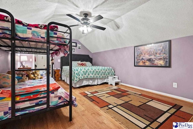 bedroom with lofted ceiling, hardwood / wood-style floors, a textured ceiling, and ceiling fan