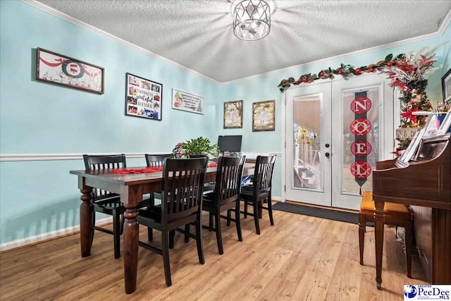 dining area with crown molding, french doors, and light wood-type flooring