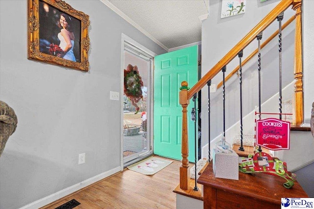 foyer featuring crown molding, hardwood / wood-style floors, and a textured ceiling