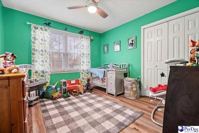 bedroom featuring ceiling fan, a closet, light hardwood / wood-style flooring, and a textured ceiling