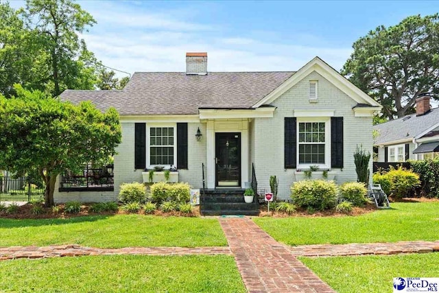 318 Mcleod St, Florence, SC 29501 - view of front of house featuring brick siding, a front yard, a chimney, and roof with shingles