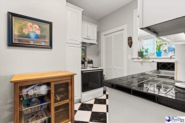 318 Mcleod St, Florence, SC 29501 - kitchen featuring range with electric stovetop, under cabinet range hood, light floors, white cabinets, and tile counters