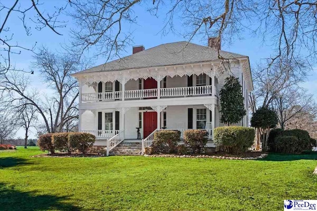 view of front of home with a front lawn, a chimney, and a porch