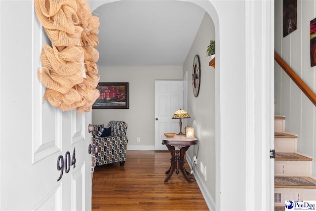 entryway featuring stairway, arched walkways, wood finished floors, and baseboards