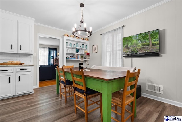 dining area featuring visible vents, an inviting chandelier, ornamental molding, and dark wood finished floors
