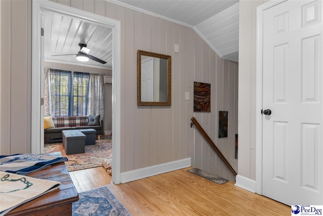 hall featuring light wood-type flooring, baseboards, an upstairs landing, and ornamental molding