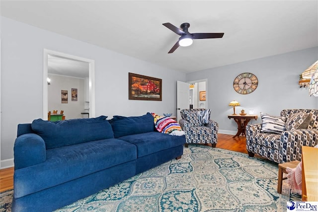 living room with wood finished floors, a ceiling fan, and baseboards