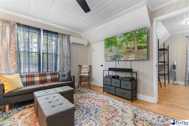 living area with vaulted ceiling, baseboards, a wall mounted air conditioner, a ceiling fan, and wood finished floors
