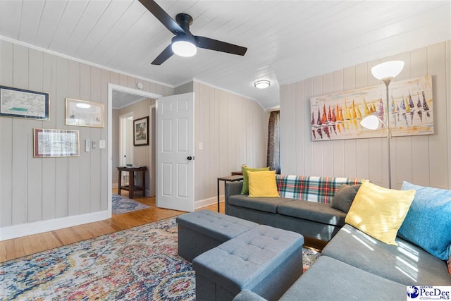 living area featuring ceiling fan, wood finished floors, baseboards, and ornamental molding