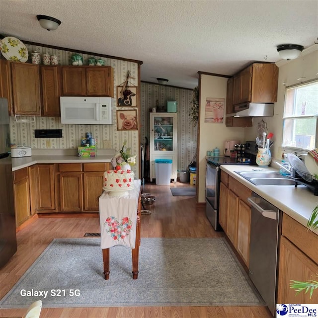 2378 Nichols Ln 2374, 2376, Effingham, SC 29541 - kitchen with under cabinet range hood, stainless steel appliances, brown cabinetry, a textured ceiling, and a sink