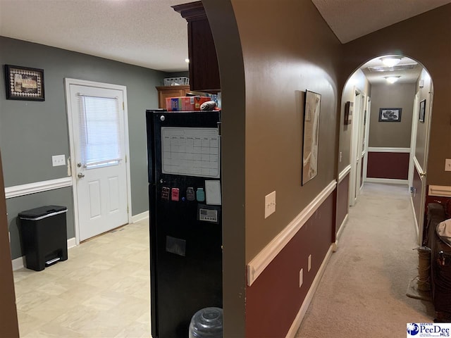 corridor with light colored carpet and a textured ceiling