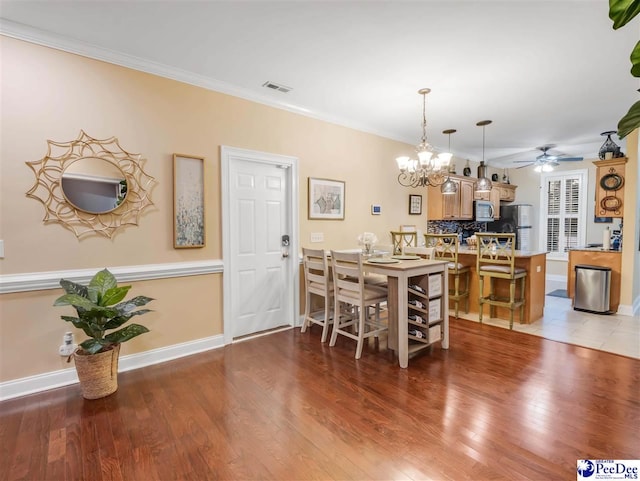 dining room with crown molding, ceiling fan with notable chandelier, and light wood-type flooring