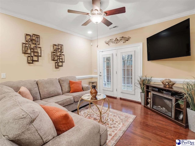 living room with ornamental molding, dark wood-type flooring, and ceiling fan