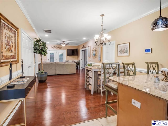 interior space featuring dark hardwood / wood-style flooring, crown molding, and ceiling fan with notable chandelier