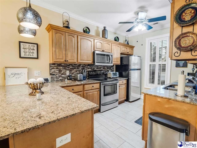 kitchen with light stone countertops, appliances with stainless steel finishes, ornamental molding, and pendant lighting