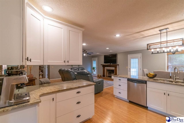 100 Warren Way, Cheraw, SC 29520 - kitchen featuring stainless steel dishwasher, a sink, white cabinets, a textured ceiling, and a fireplace with raised hearth