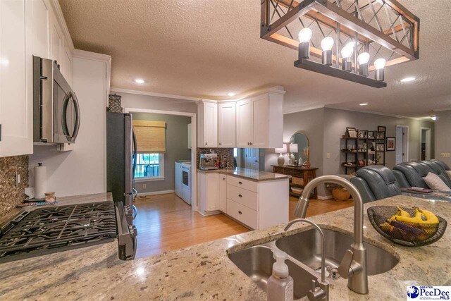 100 Warren Way, Cheraw, SC 29520 - kitchen featuring appliances with stainless steel finishes, a sink, open floor plan, light wood-style flooring, and light stone counters