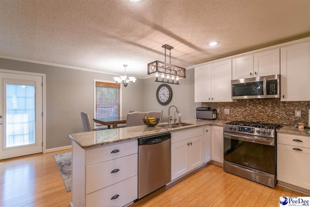 100 Warren Way, Cheraw, SC 29520 - kitchen featuring stainless steel appliances, a sink, a peninsula, a textured ceiling, and light wood-type flooring
