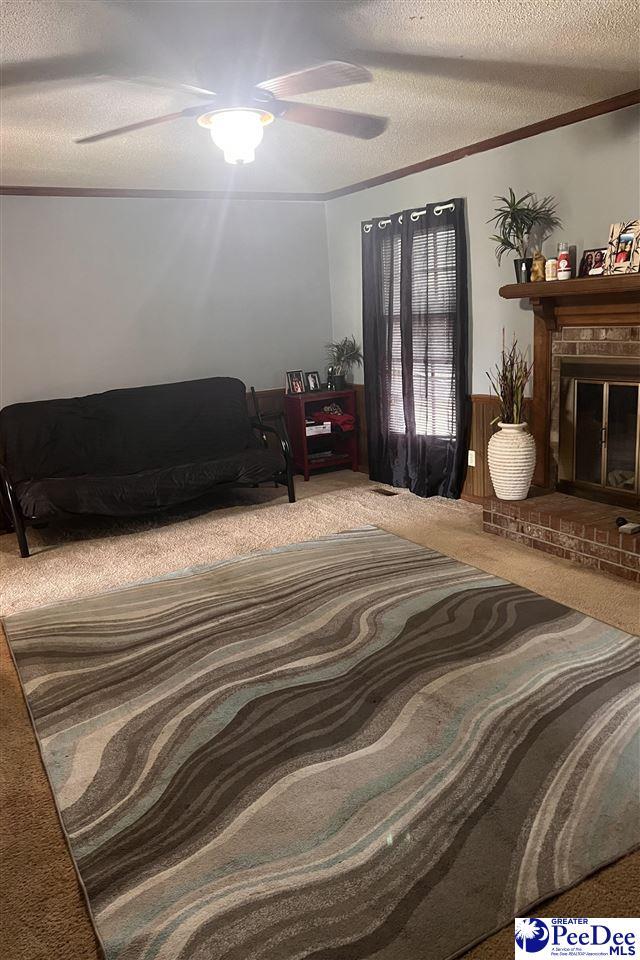 463 Chippenham Ln, Florence, SC 29501 - carpeted bedroom with a textured ceiling, ceiling fan, a brick fireplace, and crown molding