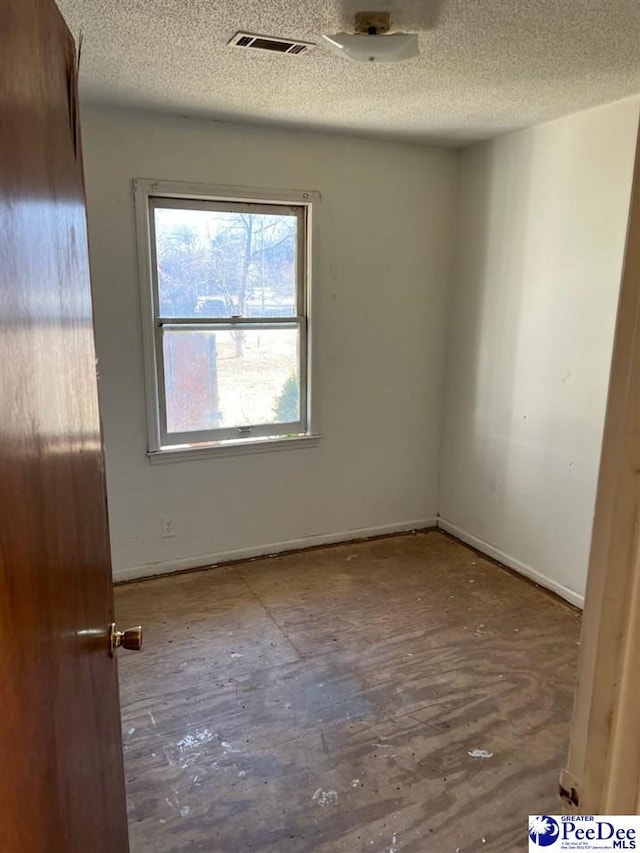 unfurnished room with visible vents, a textured ceiling, and wood finished floors