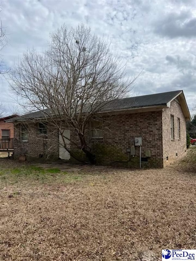 view of side of property with crawl space and brick siding