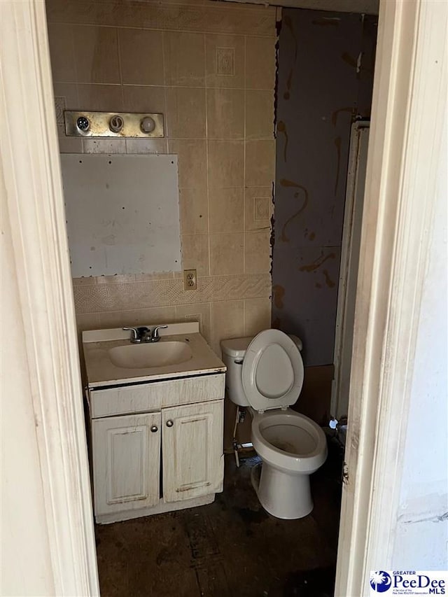 bathroom with toilet, tile walls, and vanity