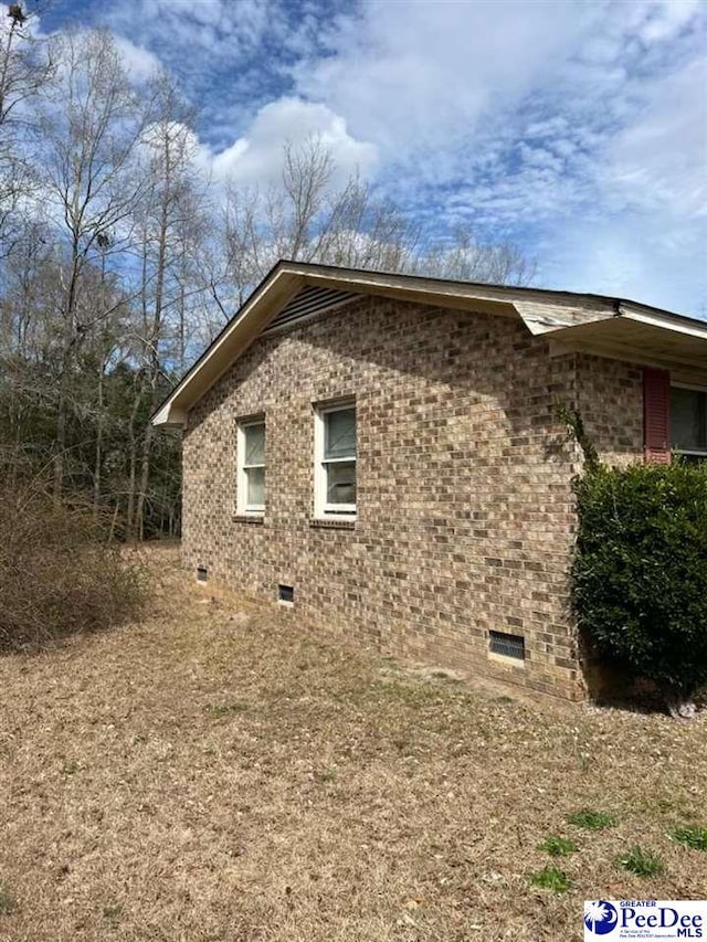 view of side of property with brick siding and crawl space