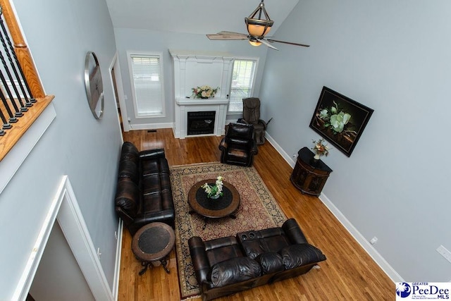 living room featuring wood-type flooring, vaulted ceiling, and ceiling fan