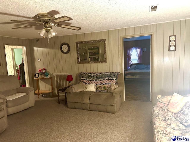 carpeted living room featuring ceiling fan and a textured ceiling