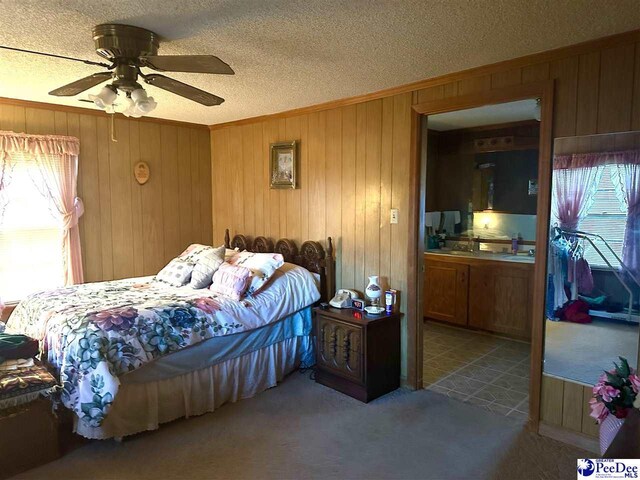 carpeted bedroom with ornamental molding, wooden walls, and a textured ceiling